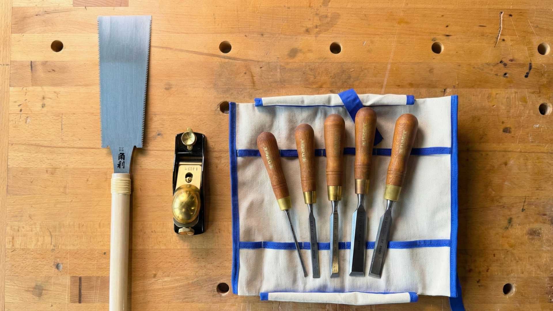 Essential woodworking hand tools for beginners including Japanese ryoba saw, bevel edge chisels, marking knife, combination square and joiner’s mallet