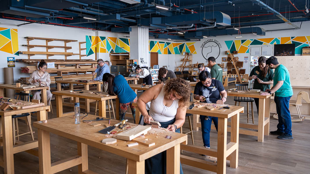 A full woodworking class in session at The Makers Society workshop in Dubai, with students working at benches