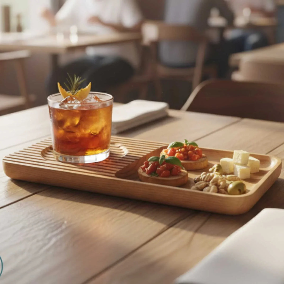 Ashwood cocktail snack tray with a glass of iced cocktail garnished with orange and rosemary, served with bruschetta, cheese cubes, nuts, and olives on a wooden table
