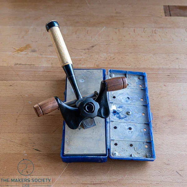 Vintage manual hand plane woodworking tool with wooden handles on blue metal box on wooden surface