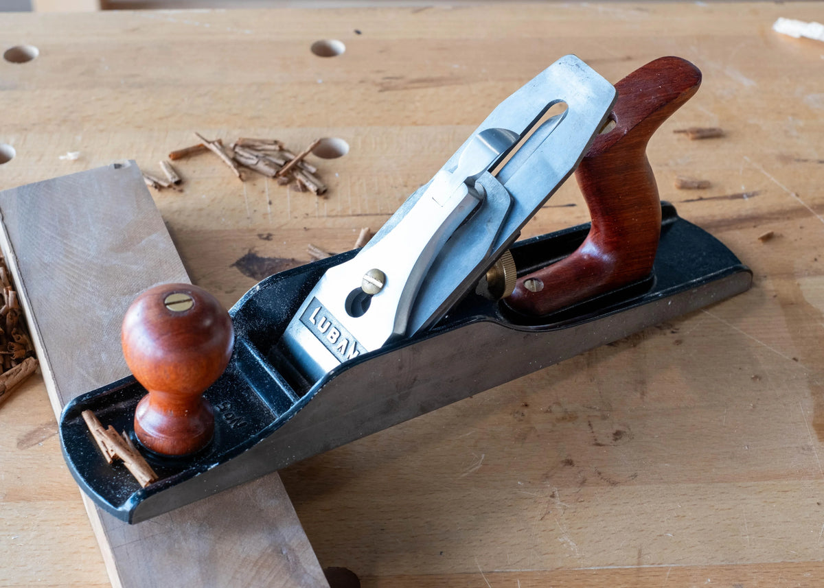 Luban 5 bench plane woodworking hand tool with wooden handles on a workbench with wood shavings