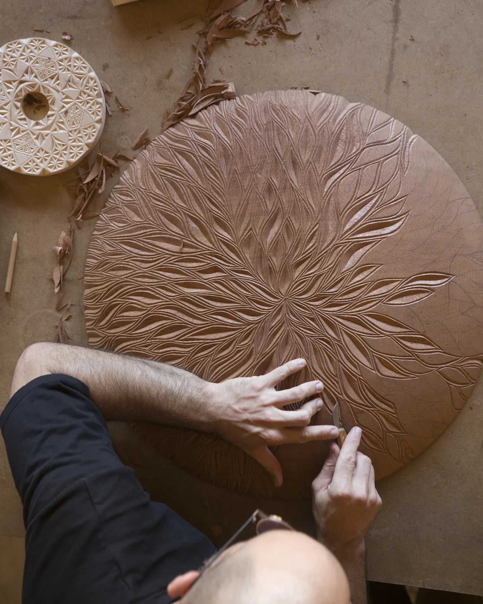 Top-down view of a carved wooden mandala in progress