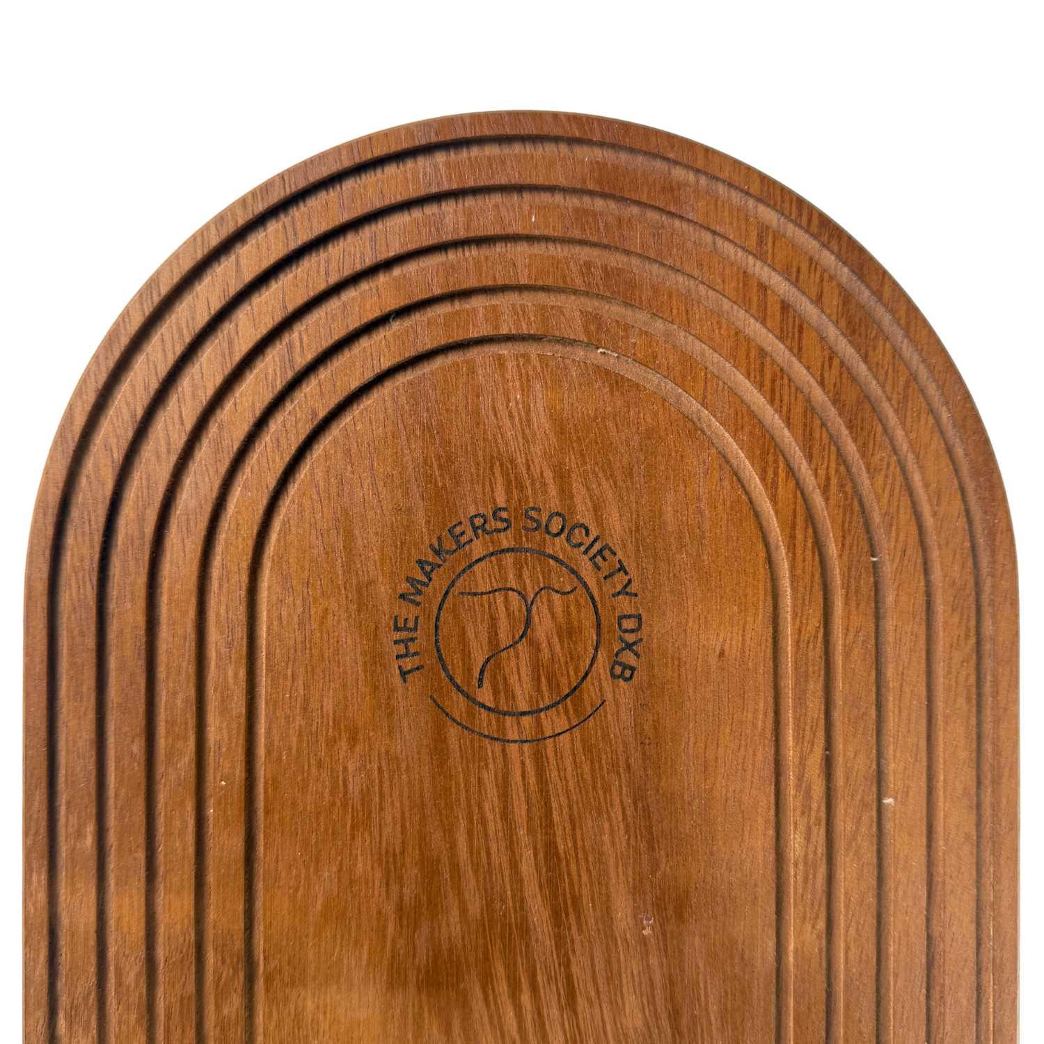 Close-up of a round, grooved wooden tray with The Makers Society DXB logo engraved in the center