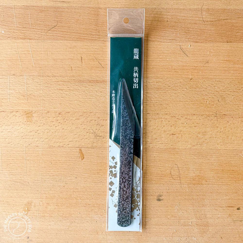 Kakuri 18mm carving knife in clear packaging on wood surface, textured blade visible