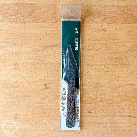 Kakuri 18mm carving knife in clear packaging on wood surface, textured blade visible