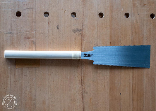 Kakuri double edge razor saw with white handle on wooden workbench, premium woodworking hand tool