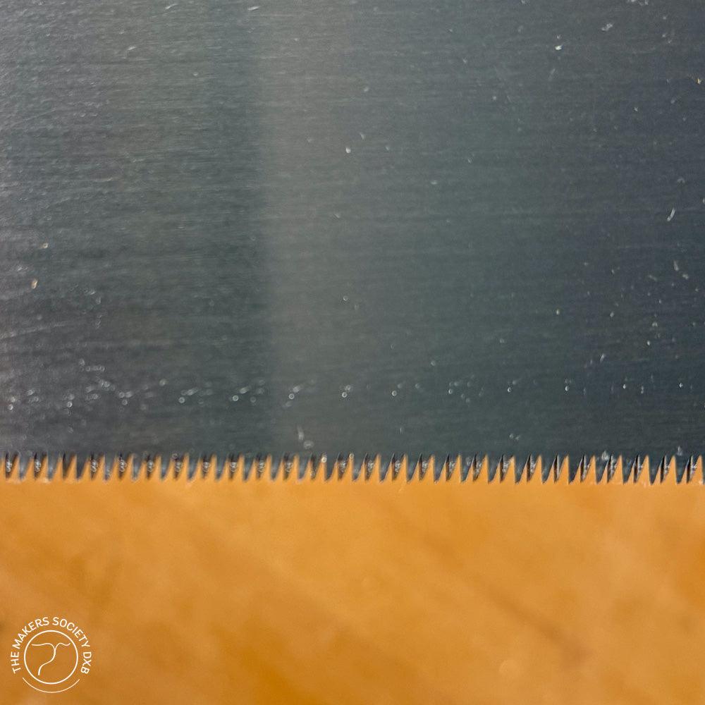 Close-up of Kakuri Japanese double edge razor saw blade with fine sharp teeth on wooden background