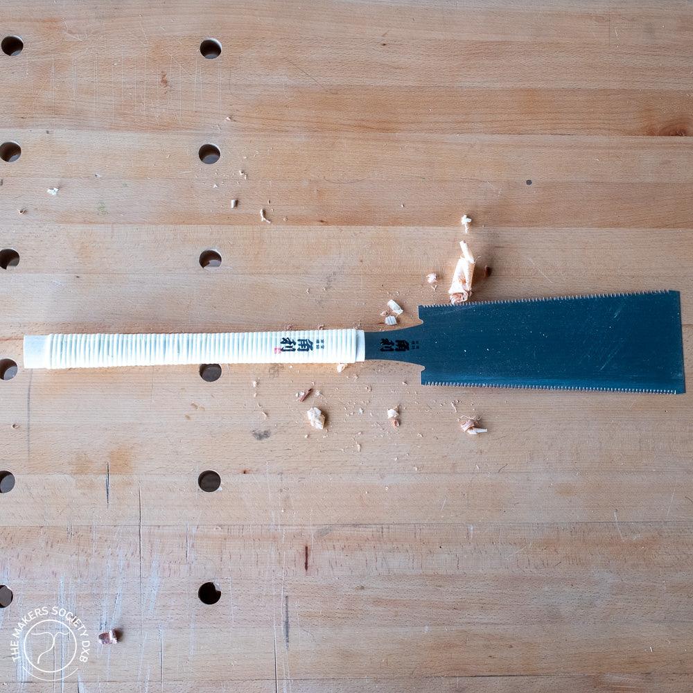 Japanese Kakuri Ryoba Saw 240mm with taped handle on wooden workbench with wood shavings