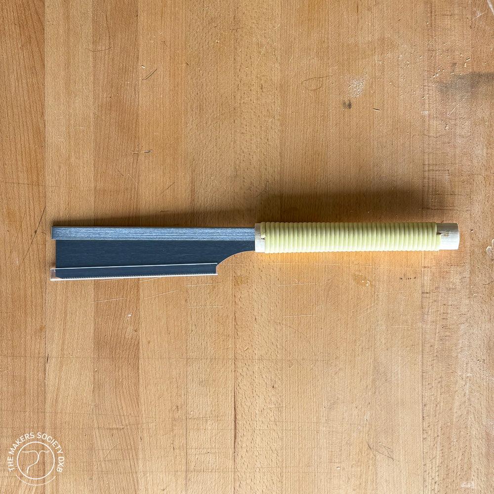 150mm Kakuri Dozuki saw with a ribbed yellow handle lying on a wooden surface, premium woodworking tool
