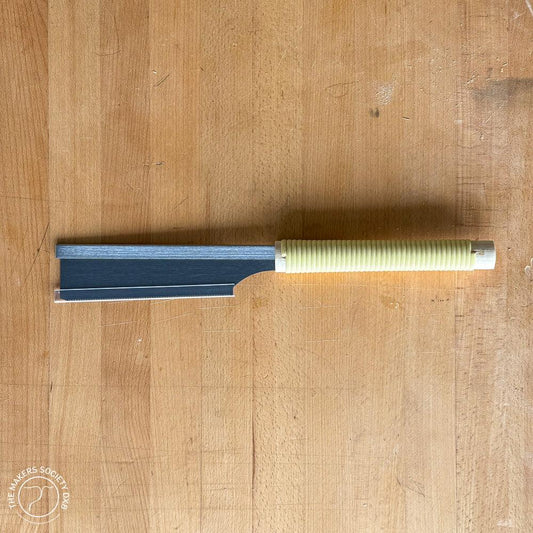 150mm Kakuri Dozuki saw with a ribbed yellow handle lying on a wooden surface, premium woodworking tool