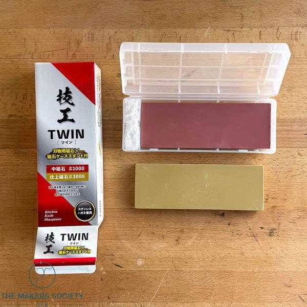 Gikoh Twin whetstone 1000-3000 grit kitchen knife sharpener with plastic case on wooden surface