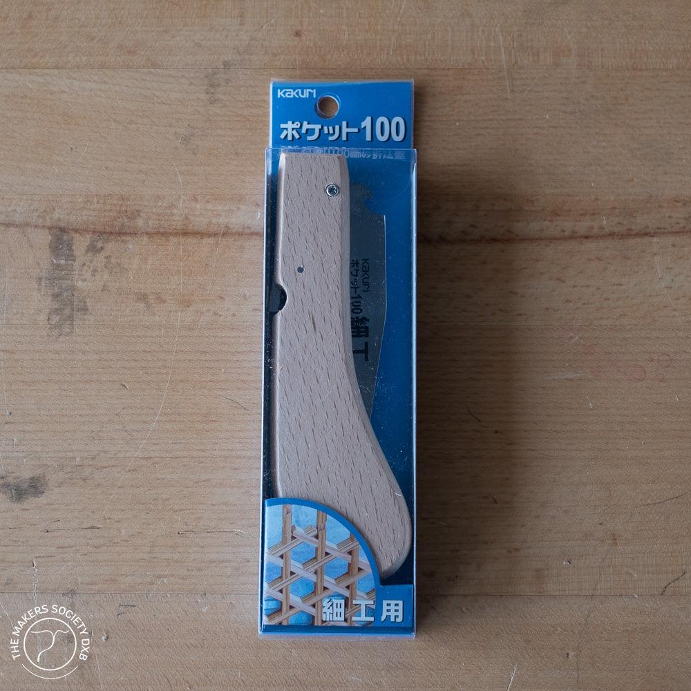 Kakuri Mini Folding Saw Pocket 100 in packaging with wooden handle, on wood surface
