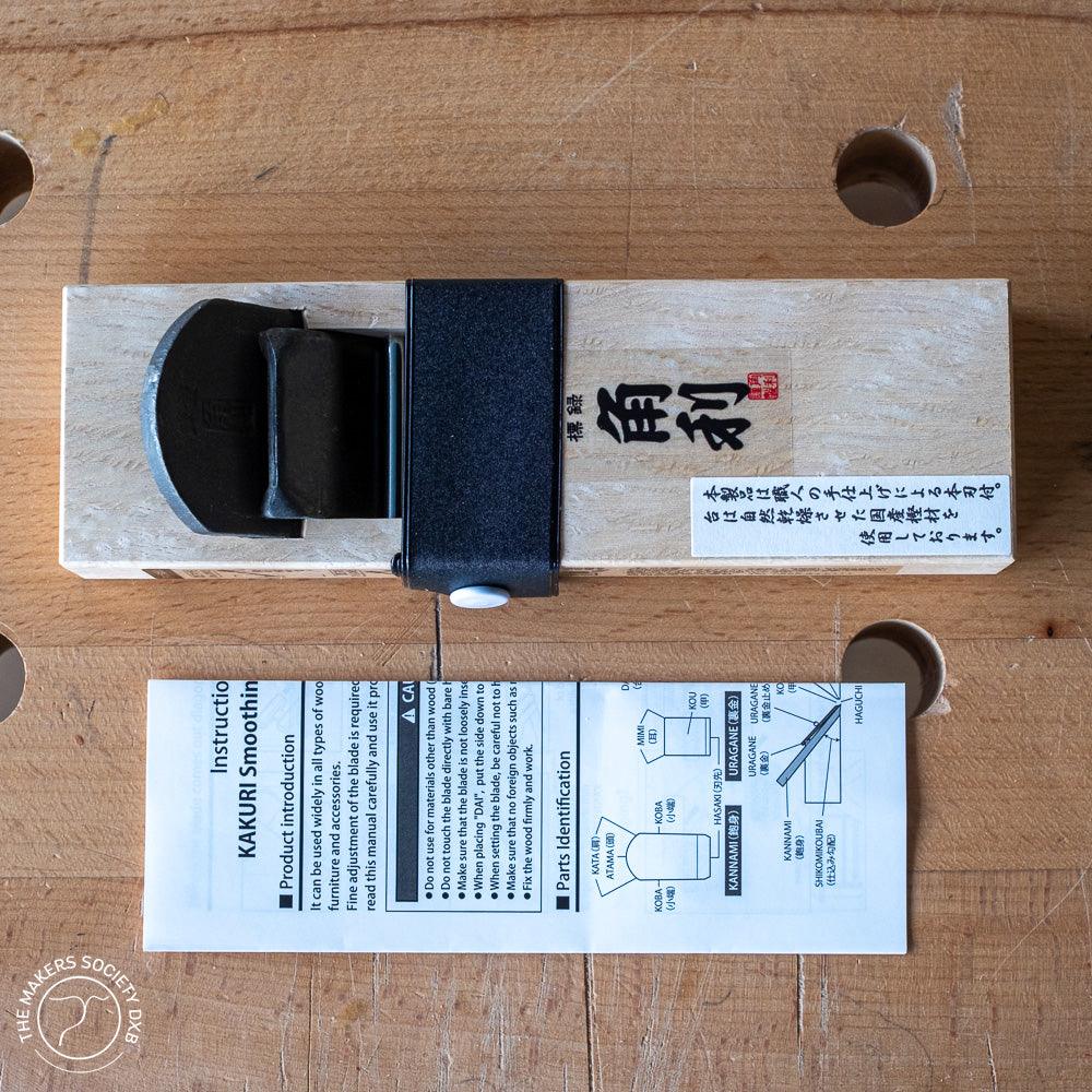 Kakuri Mini Plane woodworking hand tool with white oak body and black blade on wood surface