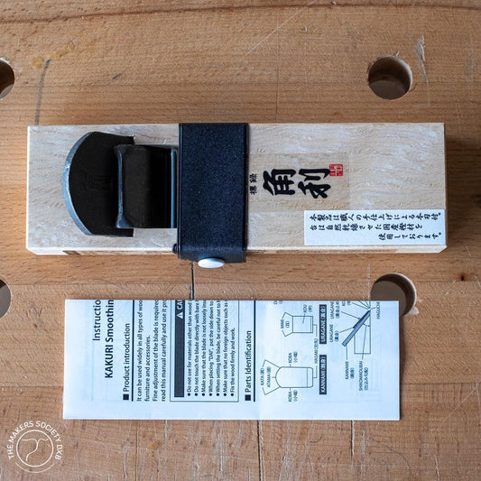 Kakuri Mini Plane woodworking hand tool with white oak body and black blade on wood surface