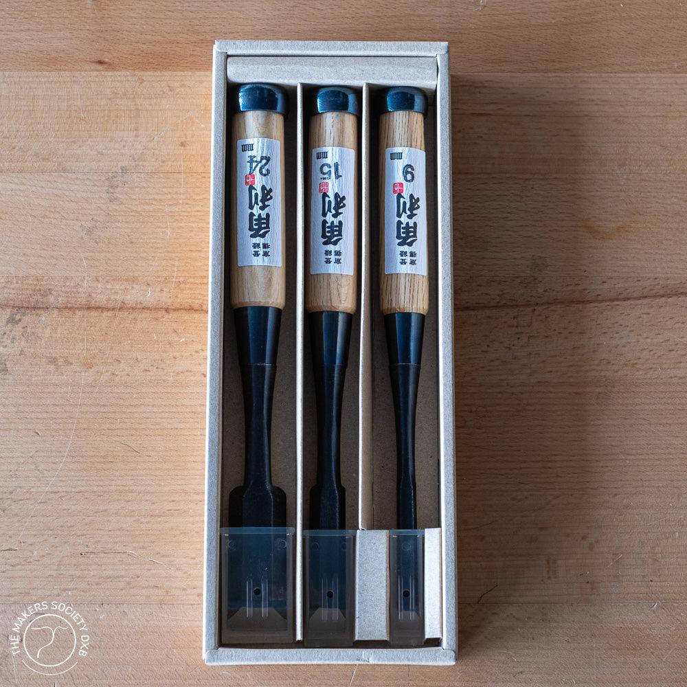 Set of three Kakuri Oire Japanese woodworking chisels with wooden handles in a box on a wooden surface