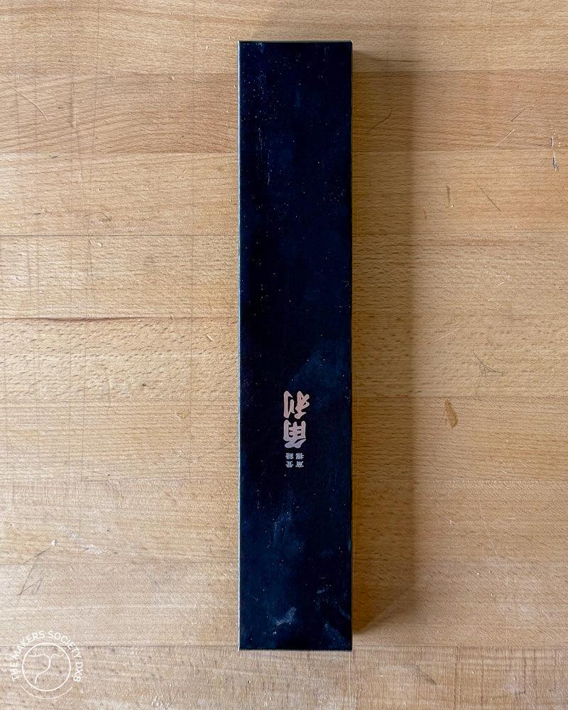 Black rectangular box packaging with Japanese characters on wood surface, woodworking tool spare blade