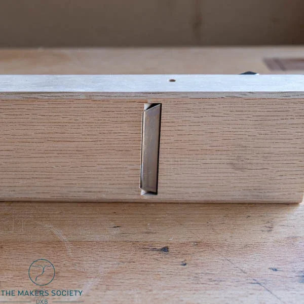 Smooth wooden hand plane with white oak body and visible metal blade, resting on wood surface