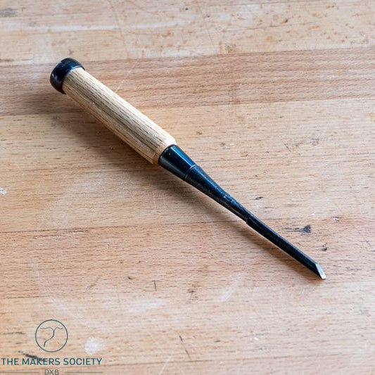 6mm wood chisel with white steel blade and wooden handle on a wooden surface