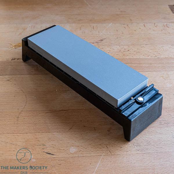 Whetstone sharpening stone on black adjustable stand for precise blade honing on wooden surface