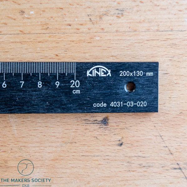 Close-up of a black Kinex metal woodworking ruler 200x130 mm on a wooden surface with visible measurement markings