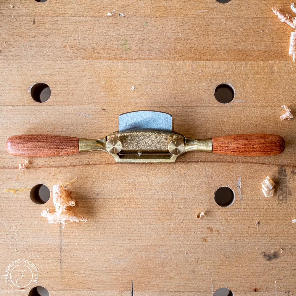 Luban Bronze spokeshave with wooden handles on a workbench with wood shavings