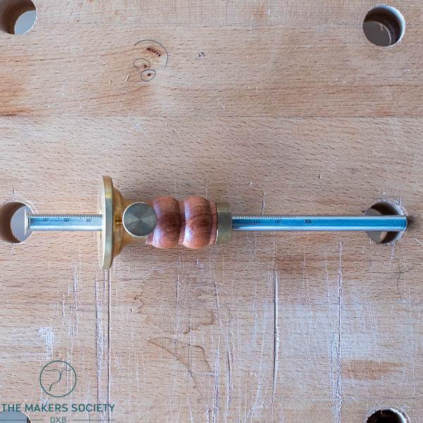 Luban marking gauge woodworking tool with brass and wooden handle on a workbench surface