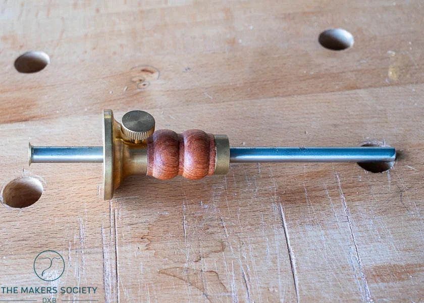 Luban marking gauge with brass and wooden handle on a woodwork bench with dog holes