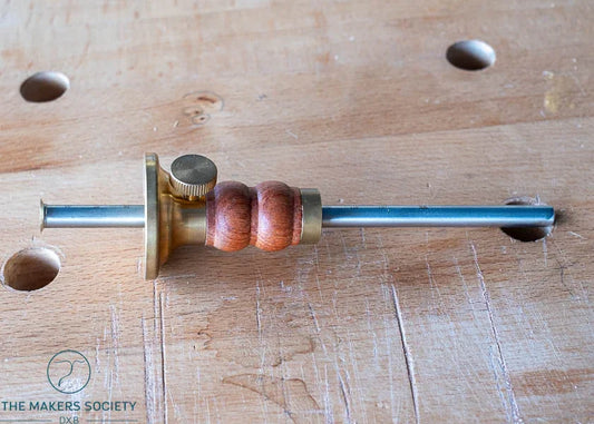 Luban marking gauge with brass and wooden handle on a woodwork bench with dog holes