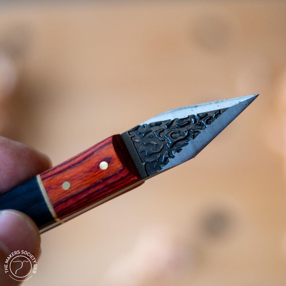 Close-up of a handmade woodworking marking knife with a textured steel blade and polished wooden handle