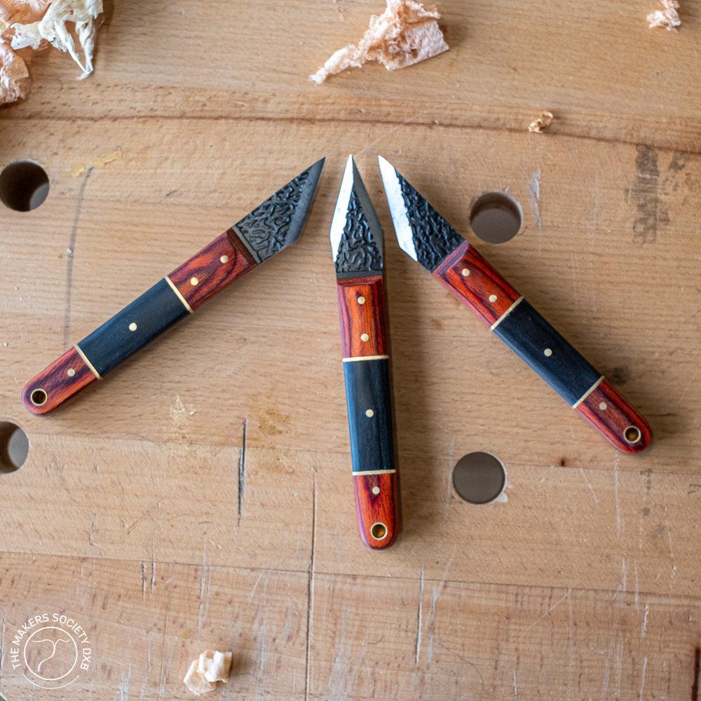 Three three-piece Luban marking knives with wooden handles on a woodworking bench with wood shavings