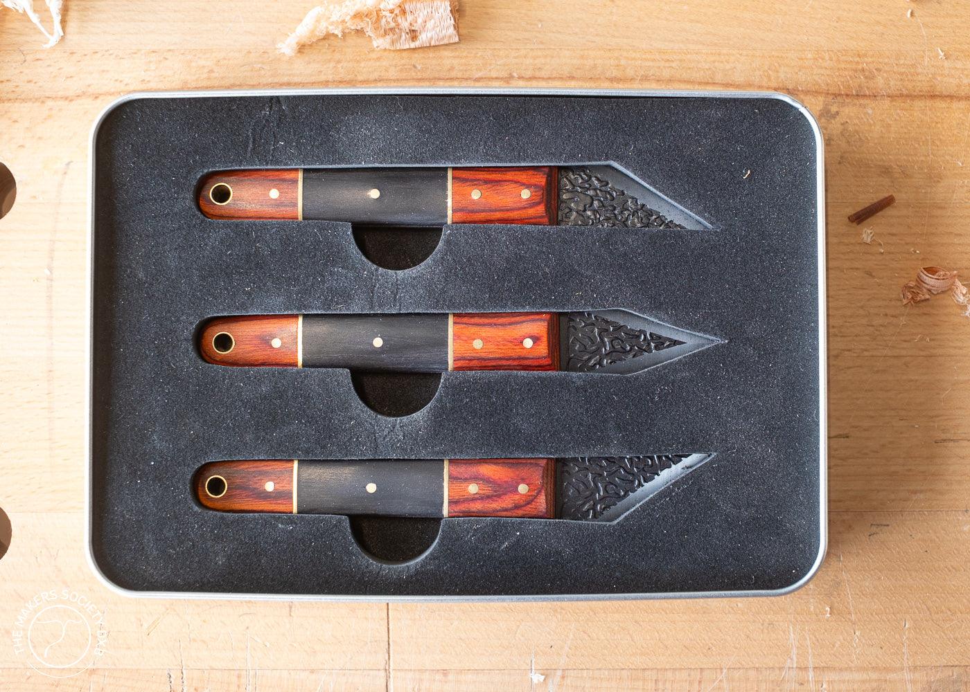 Set of three Luban marking knives with wooden handles in black foam case on wooden surface