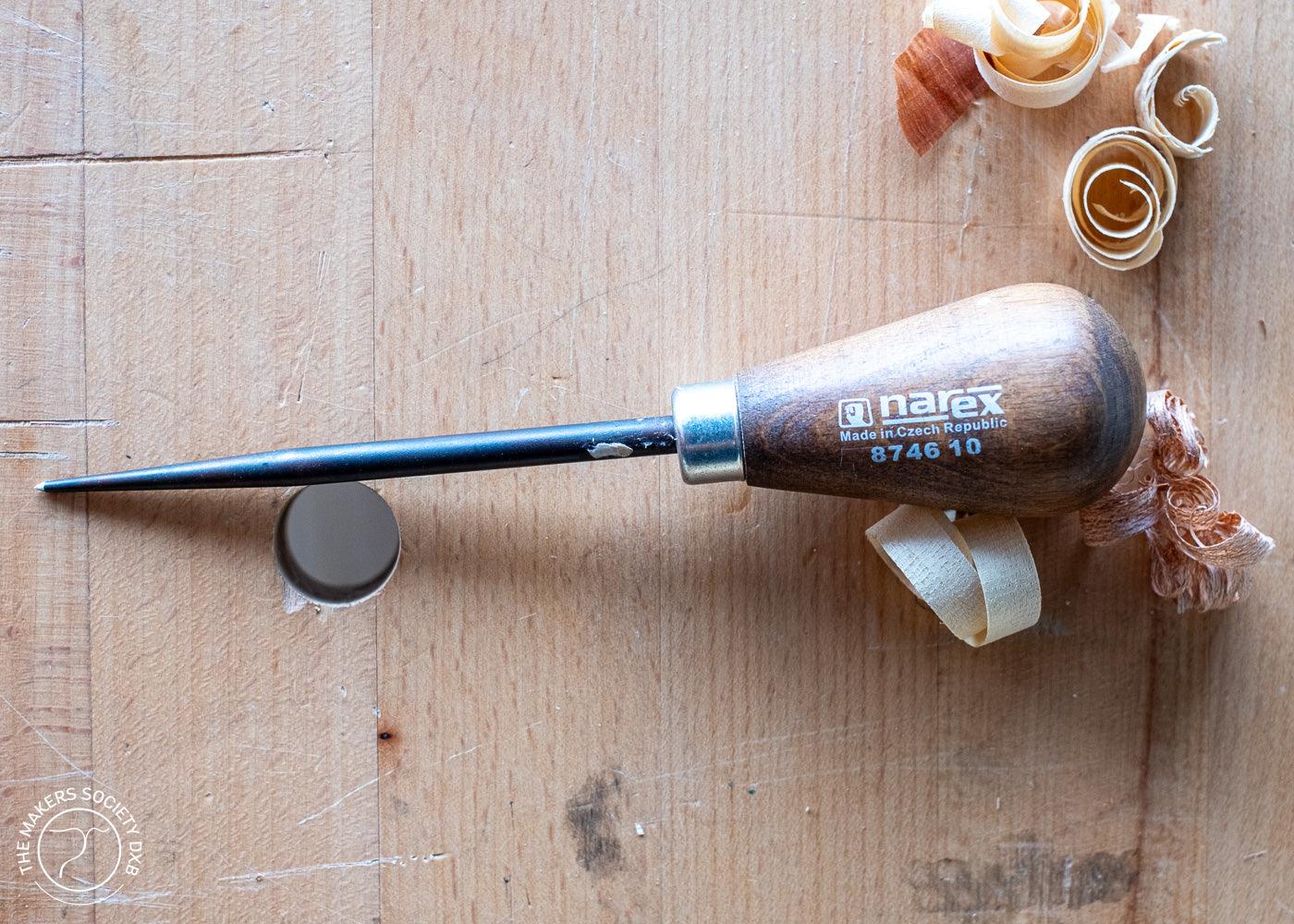 Narex woodworker awl with wooden handle and metal tip on wooden surface with wood shavings