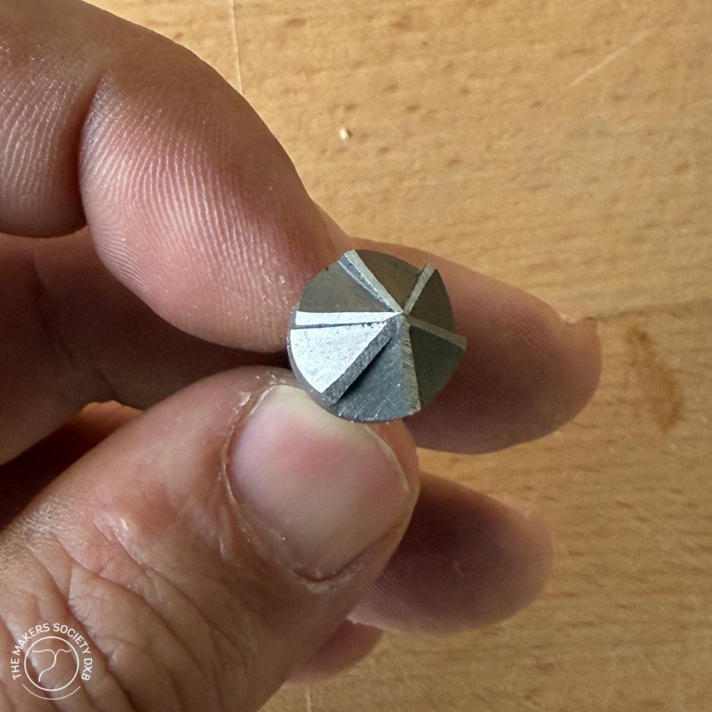 Close-up of hand holding a 12x36mm Narex conical countersink woodworking tool against wooden background