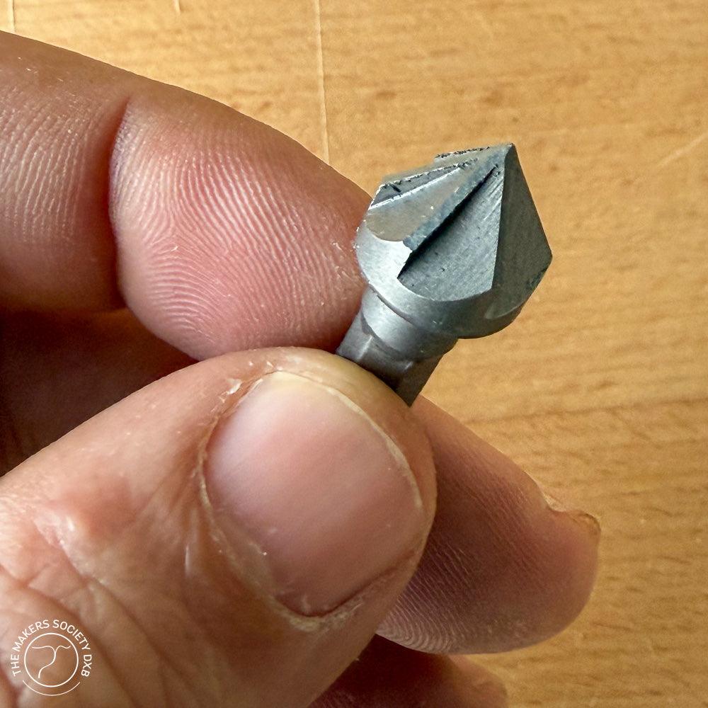 Close-up of hand holding a Narex conical countersink woodworking tool with sharp angled edges