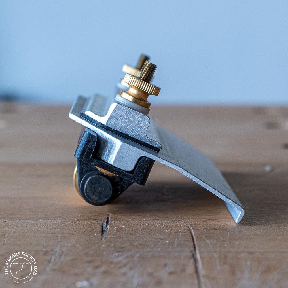 Narex honing guide with brass adjustment screws and black roller on wooden surface