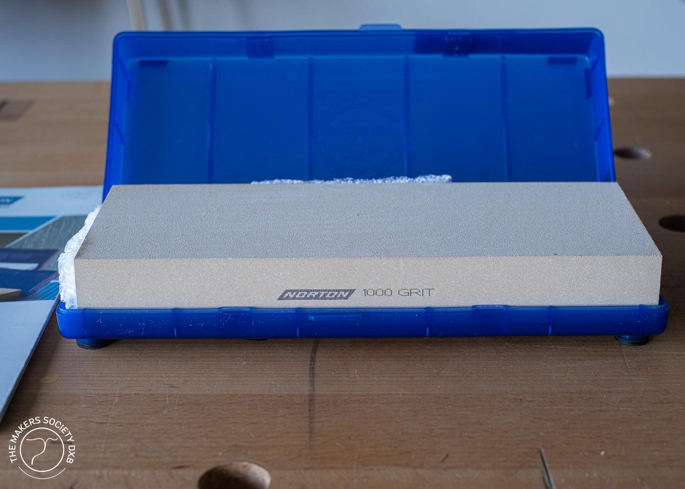 Norton Waterstone 1000 grit sharpening stone in blue plastic case on wooden workbench