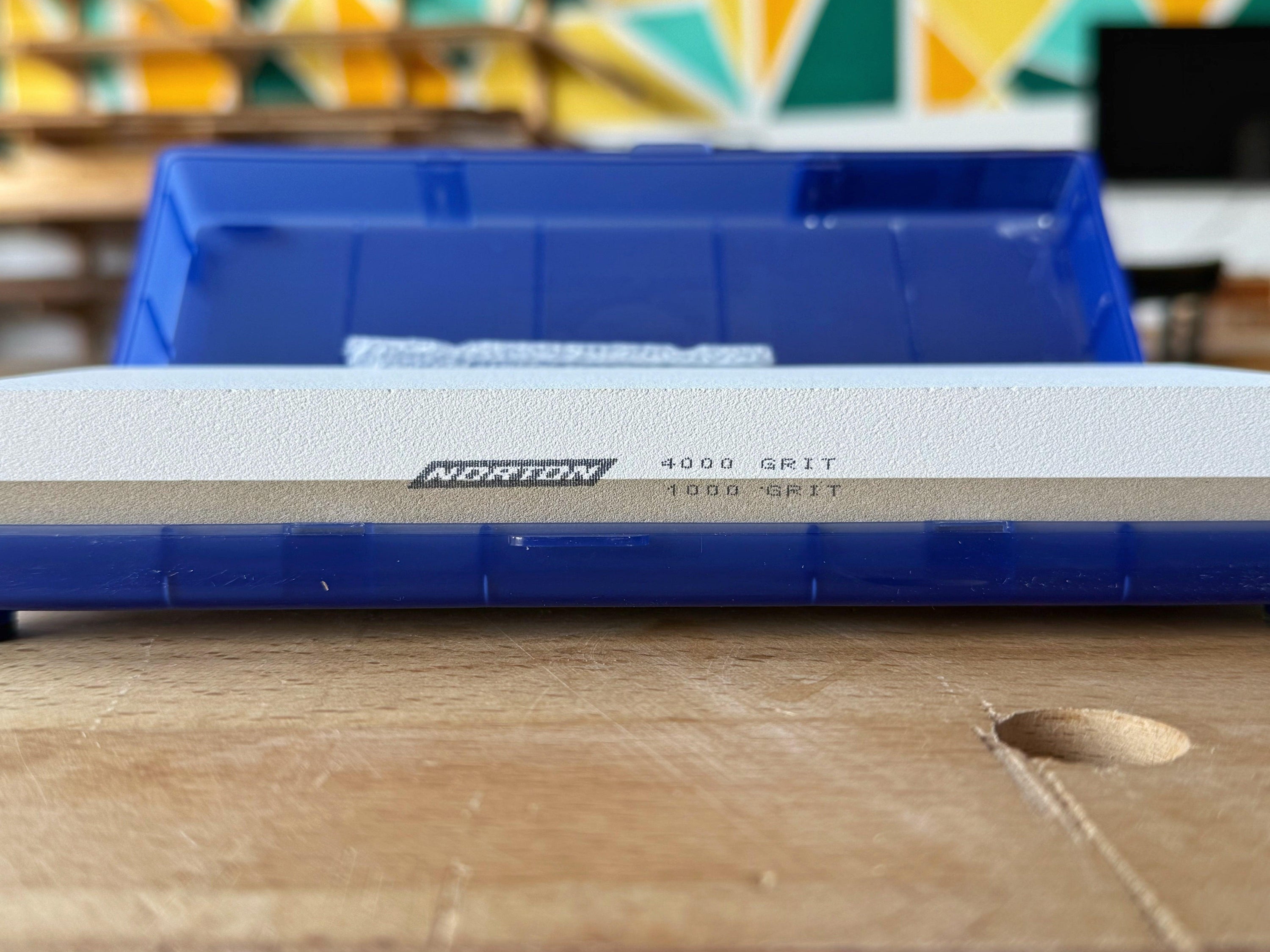 Norton Waterstone sharpening stone with 1000 grit and 4000 grit sides on blue base on wooden surface