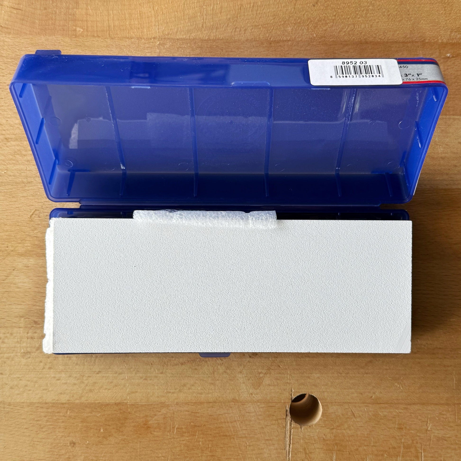 Norton Waterstone 1000/4000 grit sharpening stone in blue plastic case on wooden workbench