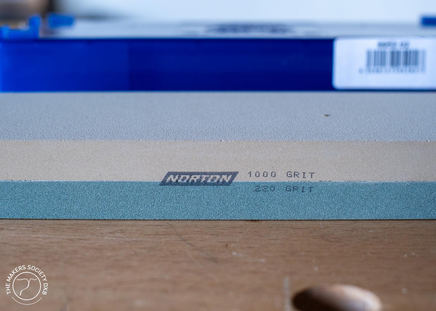 Norton Waterstone sharpening stone with 1000 grit and 220 grit sides on wooden surface