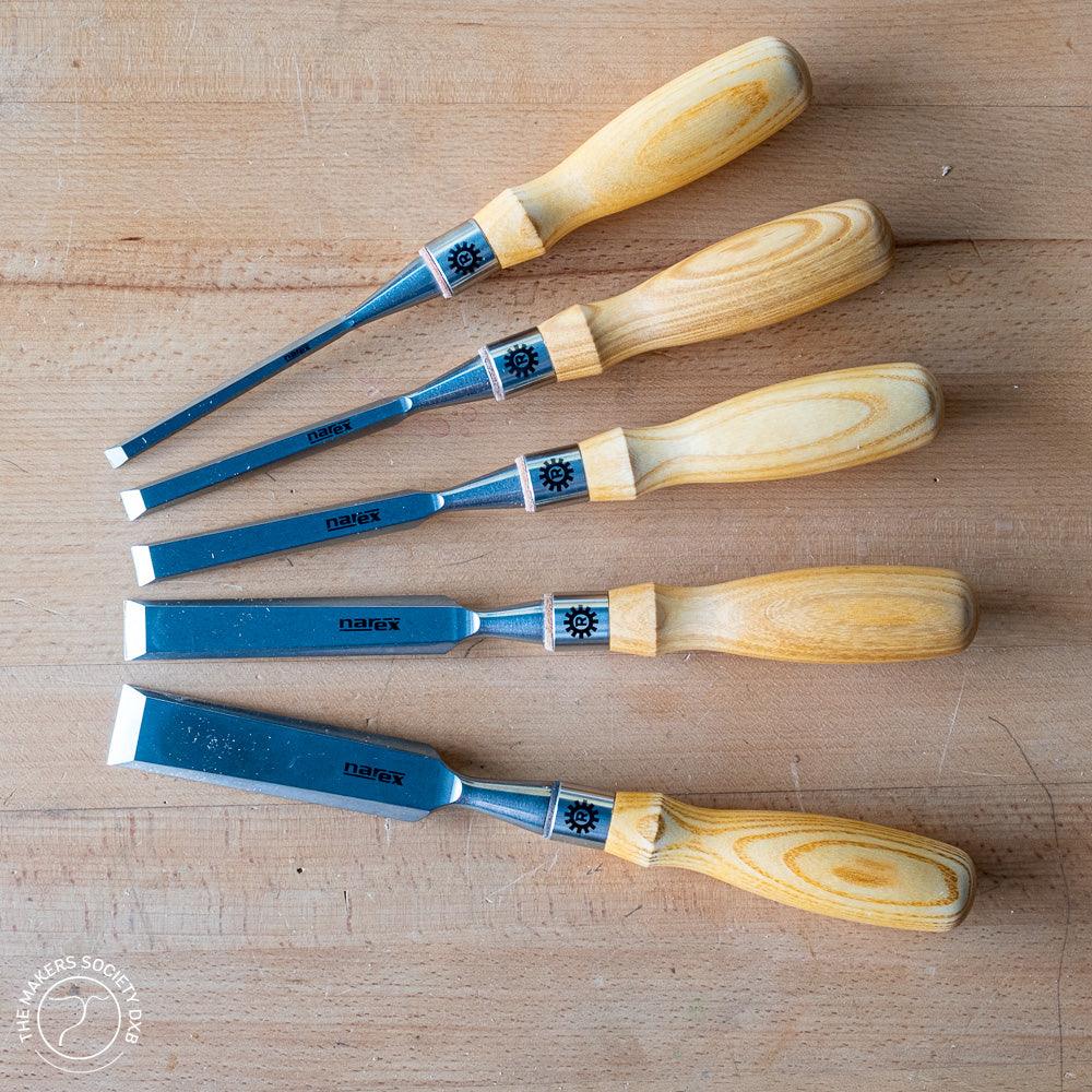 Set of five Narex bevel edge wood chisels with light wooden handles on wooden surface