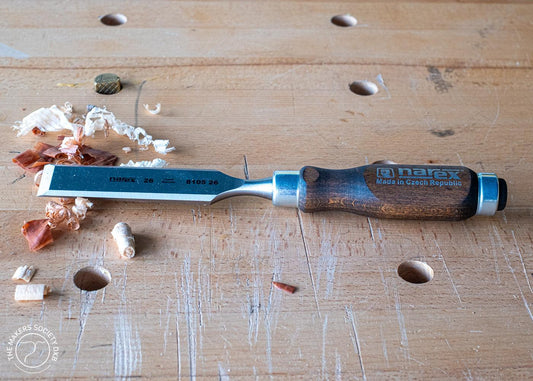 Narex bevel edge chisel with wooden handle on woodworking bench with wood shavings