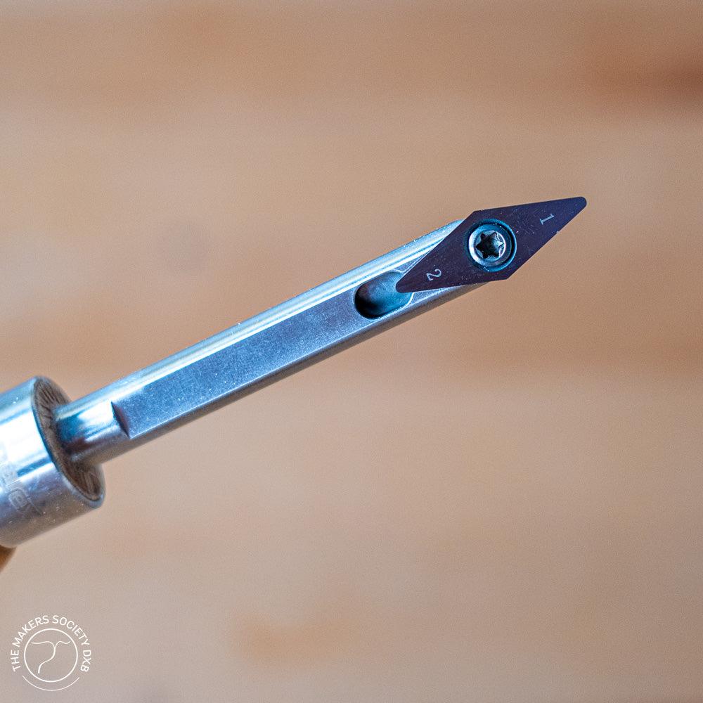 Close-up of a metal woodworking turning tool with a small triangular carbide tip, numbered 1 and 2