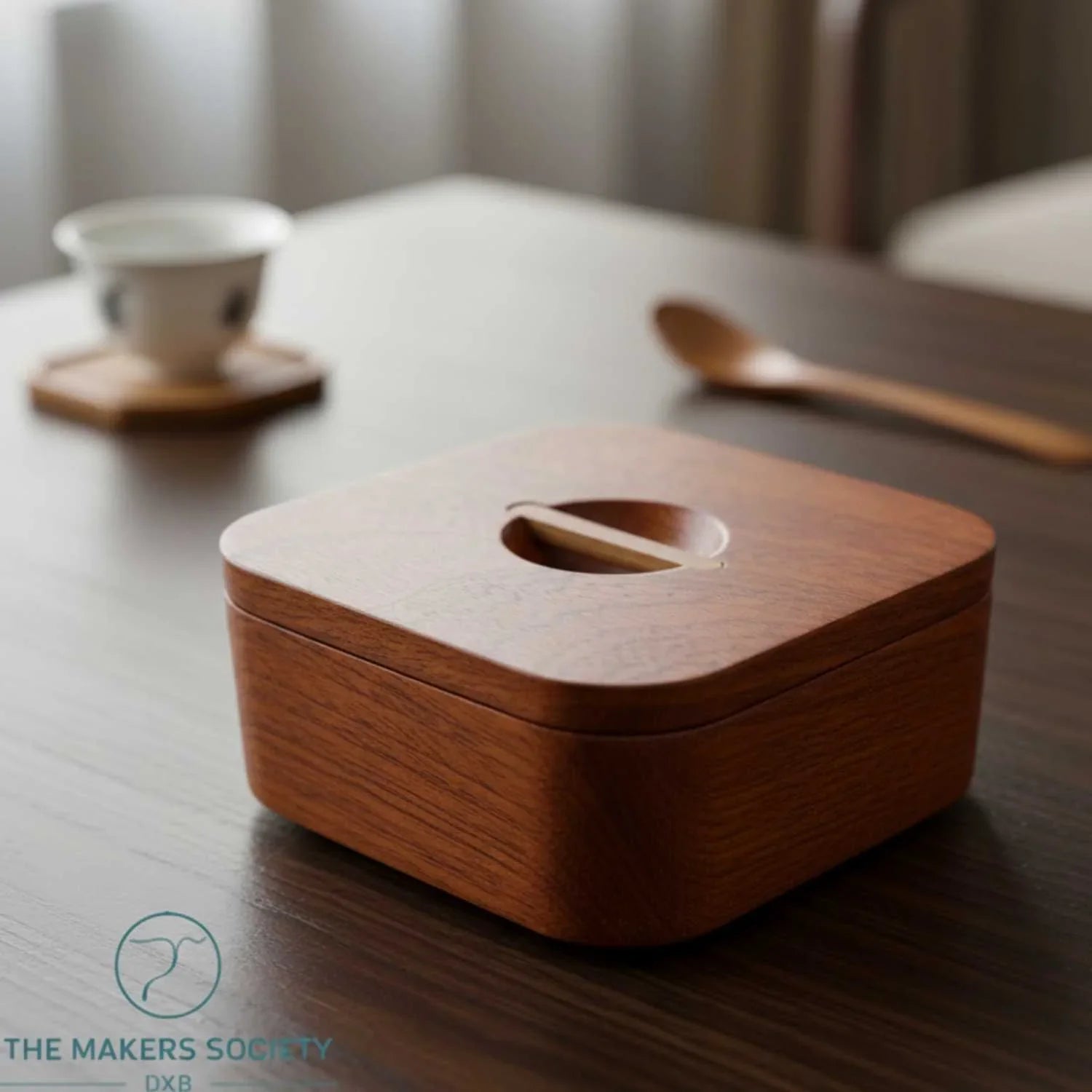 Japanese square wooden bowl with lid on dark wood table, minimalist design, tea cup and wooden spoon in background