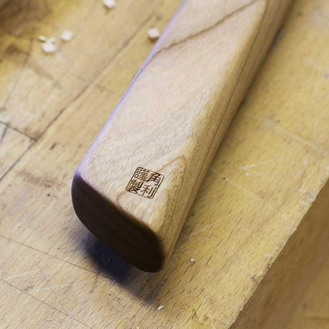Close-up of Kakuri Sakura precision tenon saw wooden handle with Japanese characters on a woodwork surface