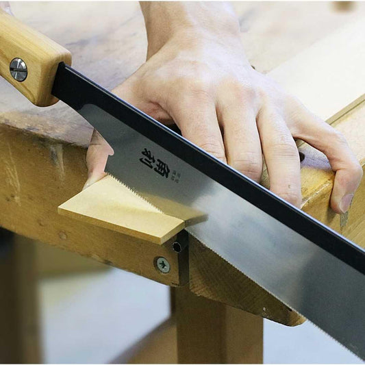 Hand using Kakuri Sakura precision tenon saw to cut a small wooden piece on a workbench