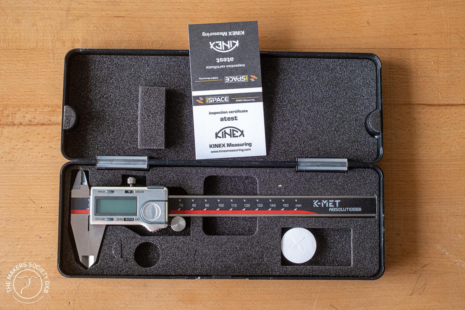 K-MET Absolute Zero digital caliper in black foam case with inspection certificate on wooden surface