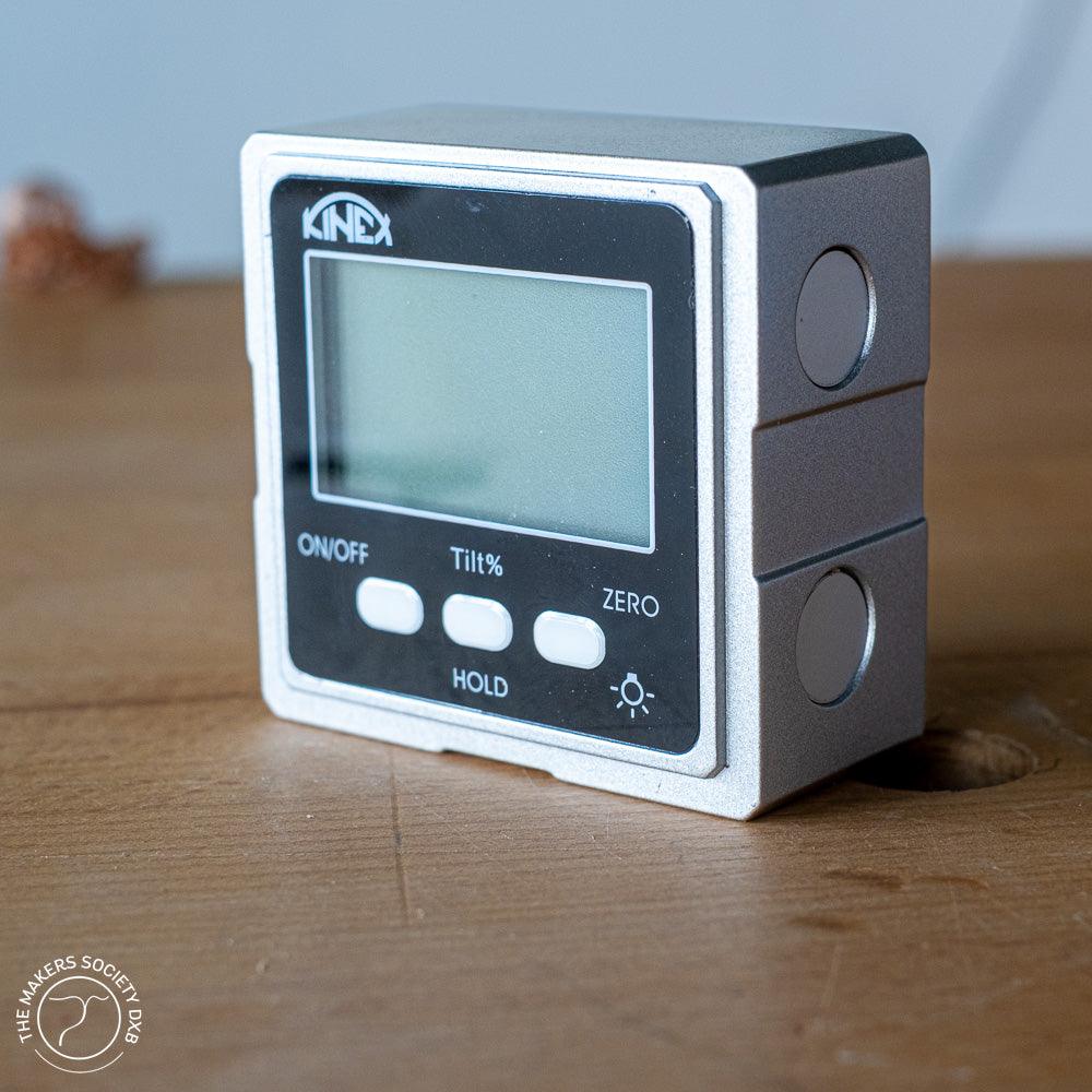 Kinex digital inclinometer with LCD screen and buttons on wooden surface, digital angle measurement tool