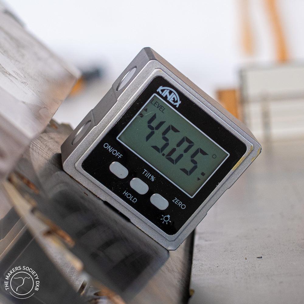 Kinex digital inclinometer measuring a 45.05 degree angle on metal surface, compact 54x54x21mm tool