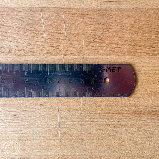 Close-up of K-MET steel ruler measuring up to 30 cm on a scratched wooden surface