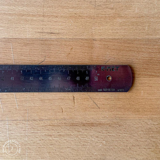 Close-up of a K-MET brand 500mm stainless steel precision ruler on wooden surface